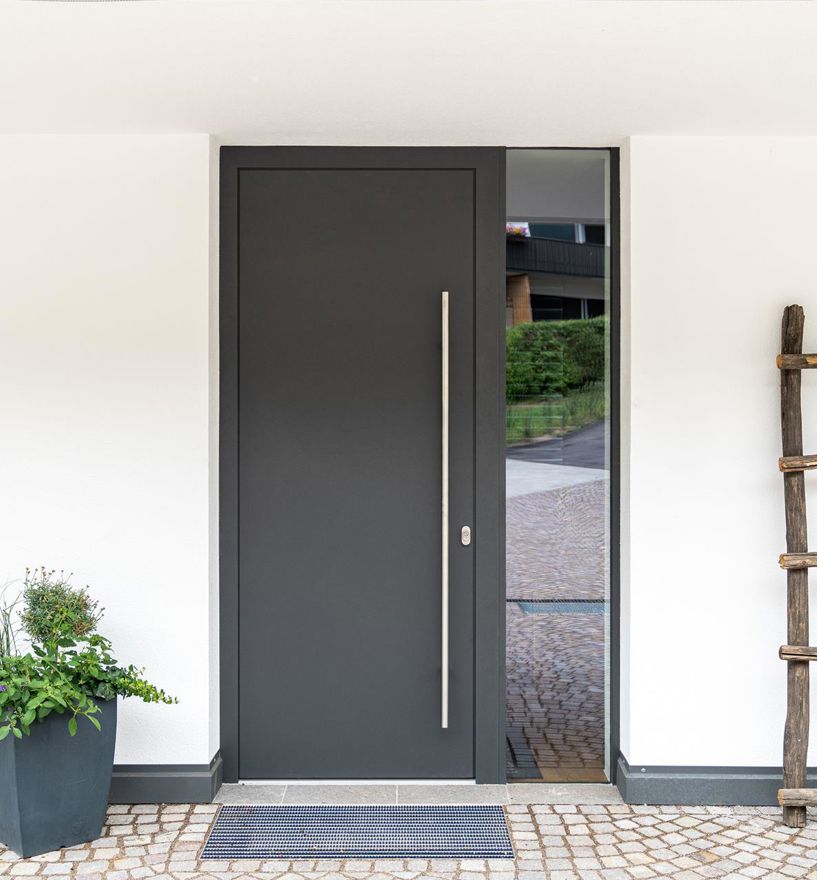 Moderne, dunkelgraue Haustür mit flächenbündigem Design und vertikalem, schlankem Edelstahlgriff und Glaselement