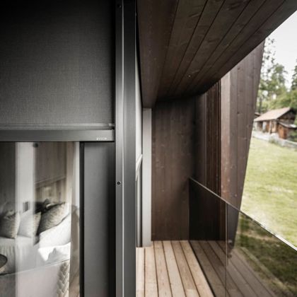 Una camera d'albergo con balcone e tende oscuranti con guida zip