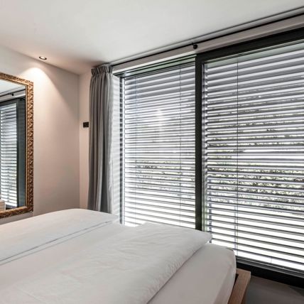 La camera di un albergo con finestre frameless e frangisole