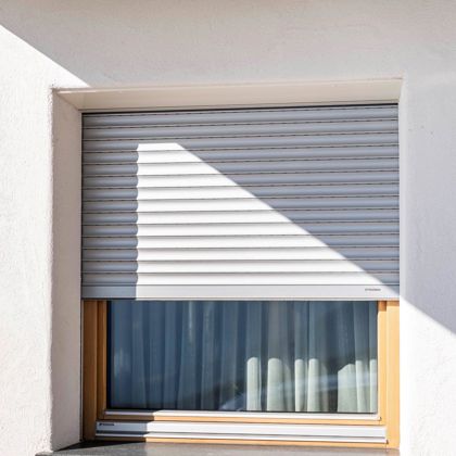 Una finestra con davanzale esterno e avvolgibili standard abbassate a metà